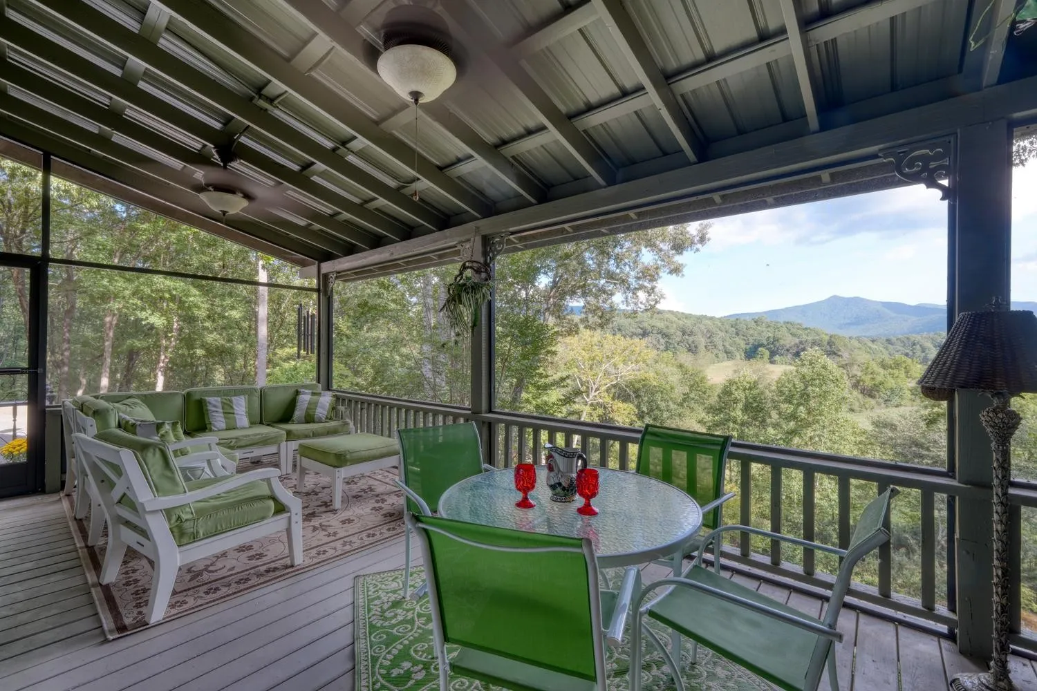 Screened porch with a wood ceiling, wicker furniture, and mountain views